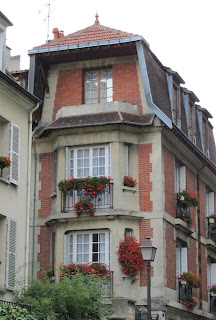 Facade of tall narrow building, brick with stone around bay windows