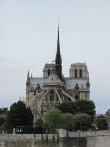Back side of Notre Dame, showing flying buttresses around a round portion and a tall narrow steeple