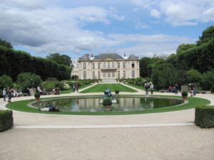 Grounds of Musée Rodin, with a large ornamental pool in the foreground and the museum in the background.