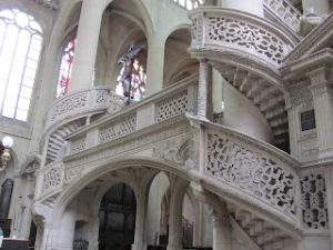 Church interior showing elevated platform flanked by two spiral staircases, all decorated with open stonework